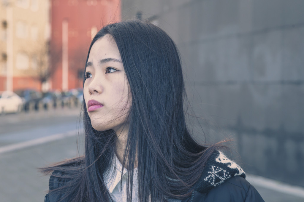 Young person walking on a sidewalk, looking upset